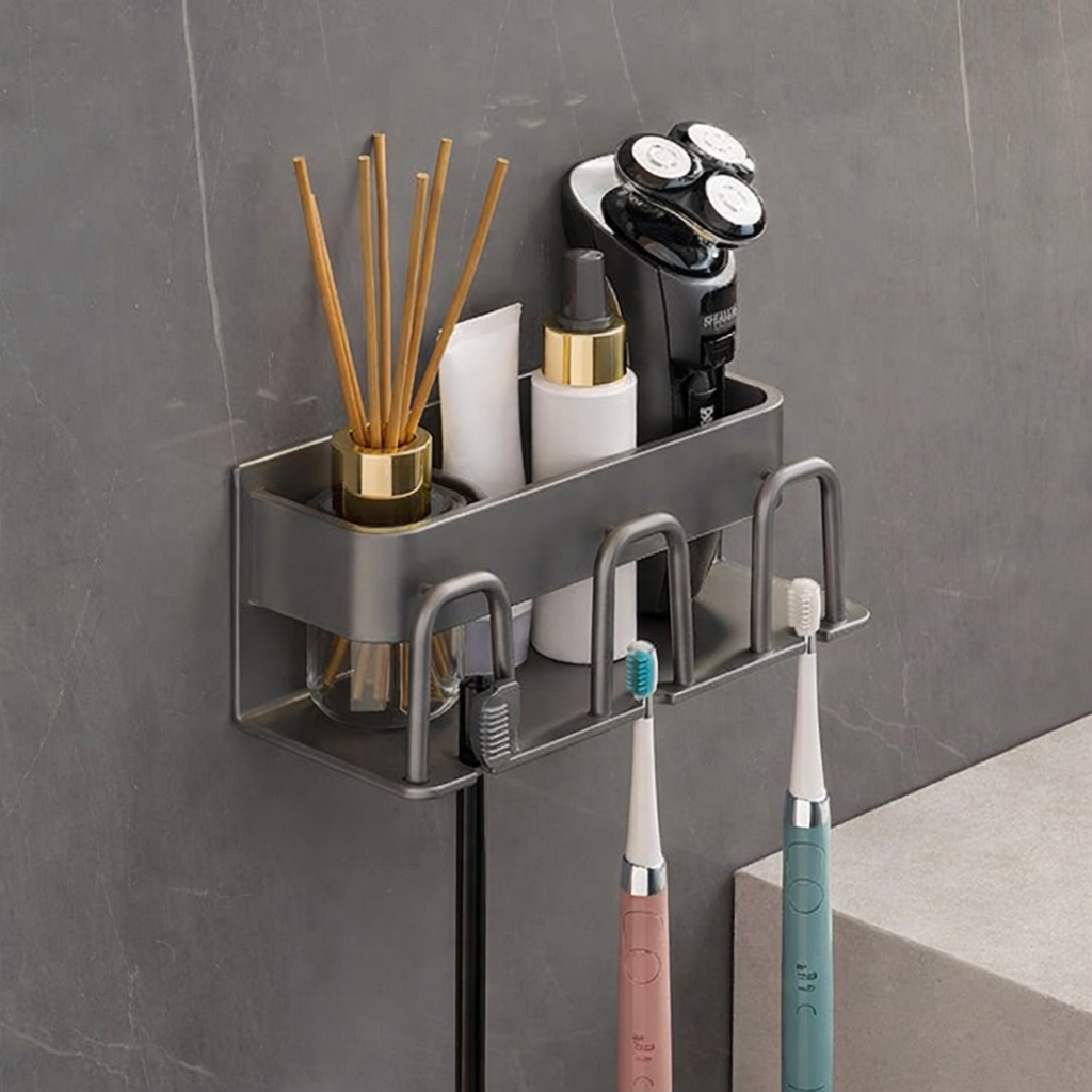 Bathroom wall caddy with various items including a razor, toothbrushes, and diffuser on a gray tiled wall.