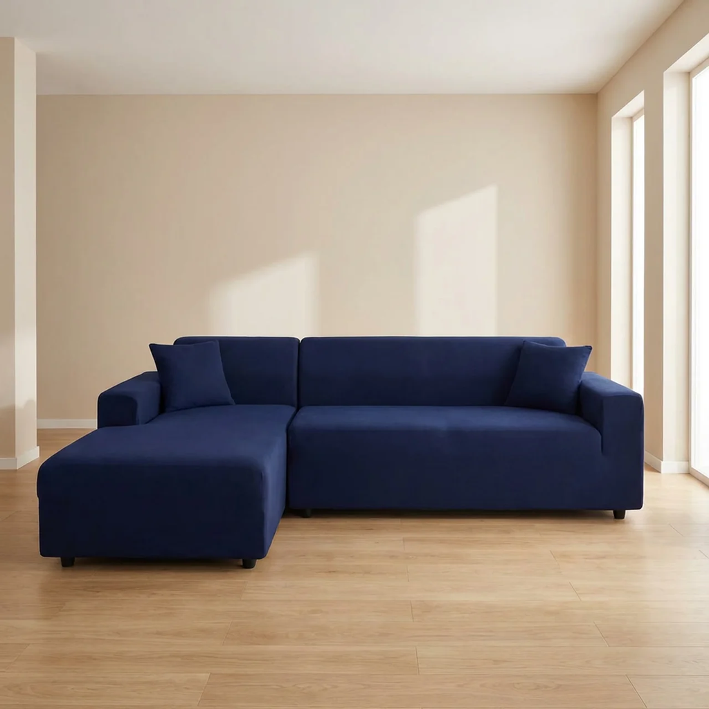 Navy blue sectional sofa in a minimalistic room with beige walls and wooden floor.