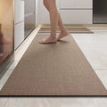 Person walking on a textured brown rug in a modern kitchen.